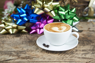Hot cappuccino or latte art coffee. A cup of coffee on the wooden table with roasted beans. Morning breakfast with coffee. Hearts shape created by pouring steamed milk.