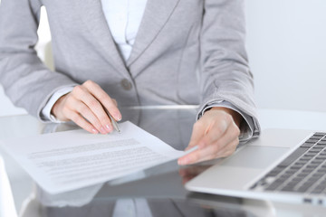 Fototapeta premium Close-up of female hands with pen over document, business concept. Lawyer or business woman at work in office