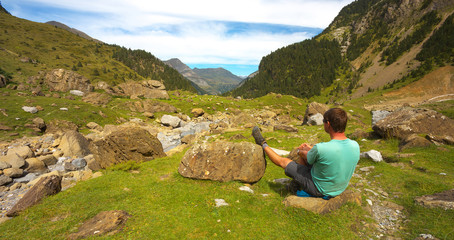Resting tourist with one leg leaning against the stone in the mountain valley nearby resort of Gavarnie, Pyrenees