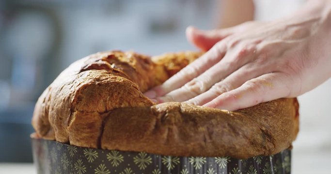 Slow motion of a chef who controls the quality of his Italian panettone by touching it with his hand to understand the softness.