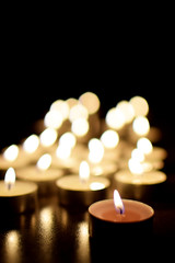 Tea light candles burning in darkness. Advent or memorial prayer candle flame.