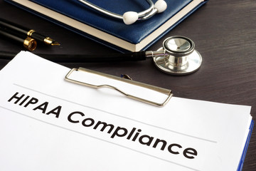 HIPAA Compliance documents with clipboard on a desk.