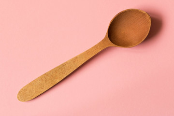 Old wooden spoon. Isolated on pink background
