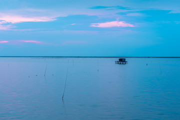 Beautiful twilight with silhouette of fisherman house on ocean.