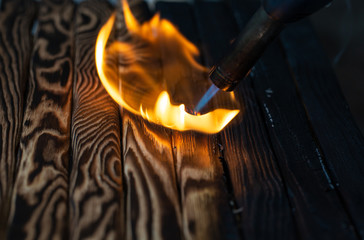 Fototapeta premium Charred wooden planks and fire. Background, texture. Flame. Wood processing.