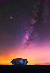 The milky way and old cottage in the field.