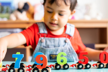 Little boy playing mathematics wooden toy at nursery