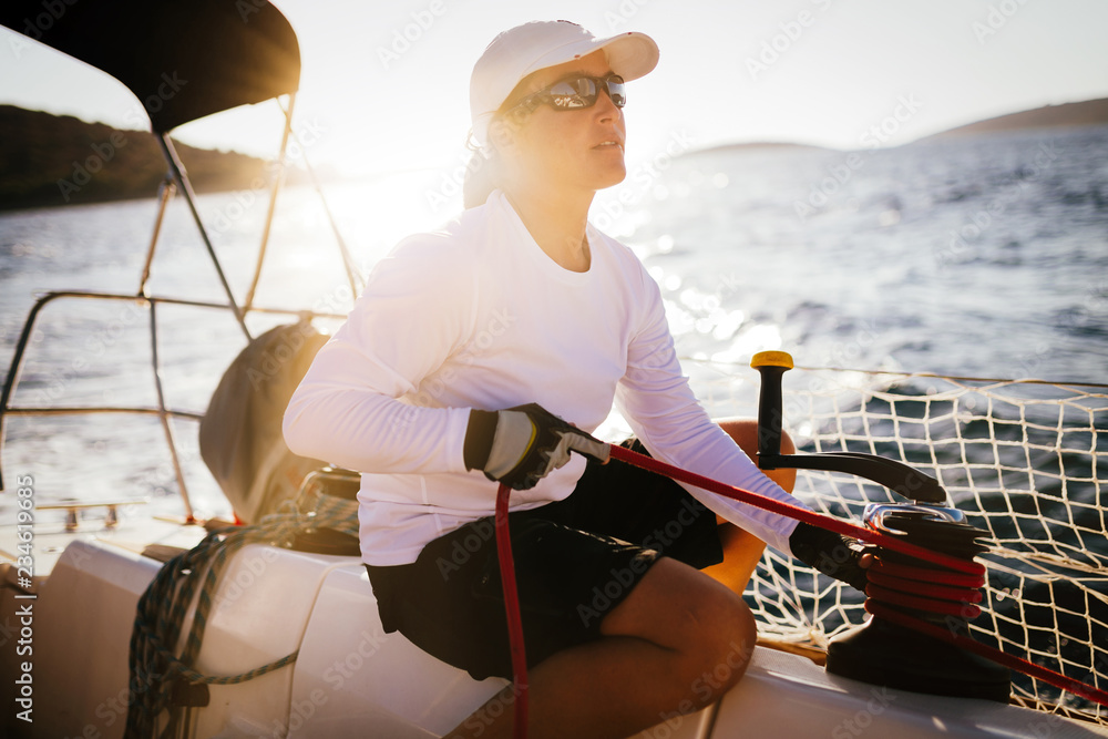 Wall mural Attractive strong woman sailing with her boat