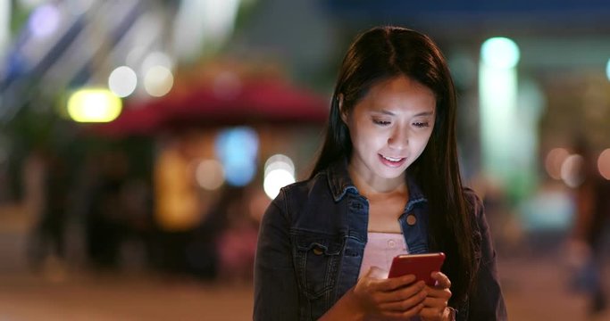 Woman search on mobile phone in city at night