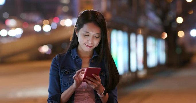 Woman stand on the road ans use of mobile phone at night