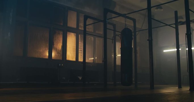 WS EST Boxing punching bag swinging in an old indoor boxing studio, no people. 4K UHD