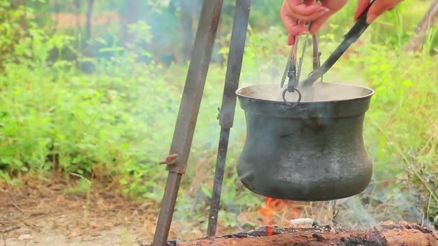 Cooking on fire in cast iron cauldron slider shoot. Cooking soup with meat and potatoes in cast iron cauldron