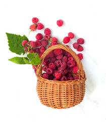 Ripe juicy raspberry berries with leaves in a basket