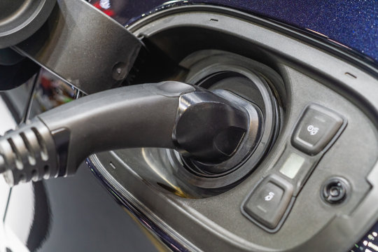 Close up image of an electric car is being charged at a charging station