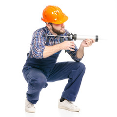 Young man builder industry worker hardhat with a silicone gun on white background isolation
