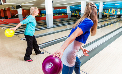 Mother and daughter enjoying bowling game in club