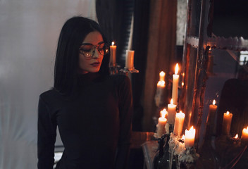 Fototapeta premium The girl in glasses, stands next to the candles
