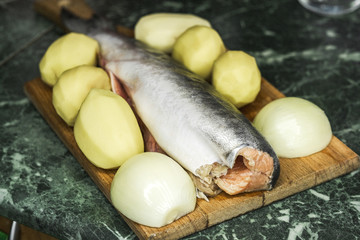 the fresh raw pink salmon potatoes and onions on cutting Board