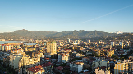 Obraz premium Batumi, Adjara, Georgia - October 2018: cityscape seen from the top of Sheraton sky bar during sunset golden hour with mountains in background