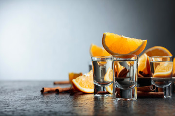 Glasses of tequila with orange and cinnamon sticks.