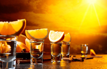 Glasses of tequila with orange and cinnamon sticks.