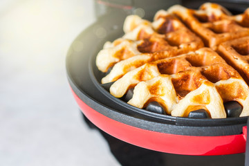 The process of making homemade waffles. Freshly baked waffles in a waffle iron.
