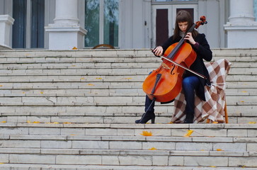 young woman playing cello on the steps of marble staircase of an ancient house © Julia