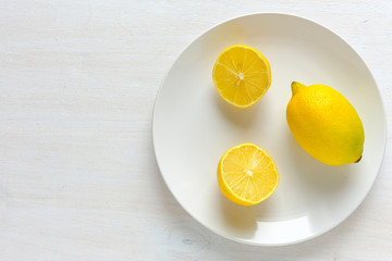 Lemon cut in half on plate with white copy space