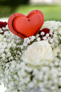 Cuore rosso decorativo sopra composizione floreale