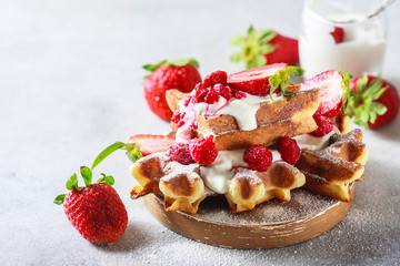 Belgian waffles with creem and raspberries and strawberries.