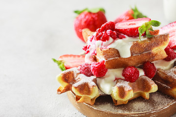 Belgian waffles with creem and raspberries and strawberries.