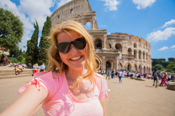 Tourist woman taking selfie in front of Colosseum in Rome
