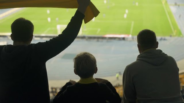 Child and men with scarves rejoicing winning goal, cheering for football team