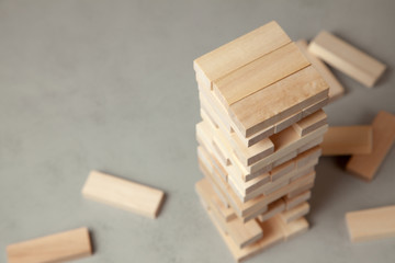 Tower of wooden blocks on gray background. Board game for the whole family or party. Concept of building business or building team. Copy space for text