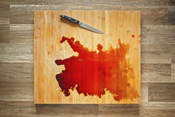 Blood and knife on the big wooden cutting board.