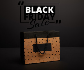 close up view of paper shopping bag on black with black friday sale