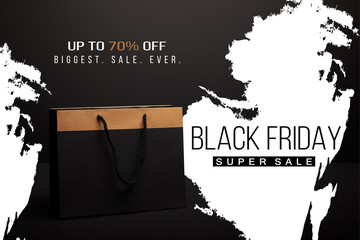 close up view of paper shopping bag on black with black friday super sale and 70 percents discount