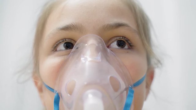 Teen's face inhaling through inhaler mask