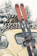 Classic car with vintage ski's and sled during snowfall