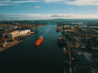 Naklejka premium Teesside transporter bridge with bulk carrier ship sailing under it showing industrial river