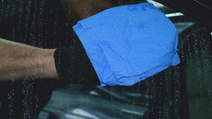 Professional car washer wipes and dries window after car washing service. Concept from: Reading...