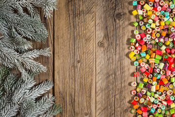 The branch of spruce with colored candies on the old wooden table.