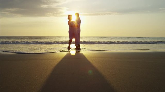 Silhouette of retired Caucasian couple dancing on the beach at sunset