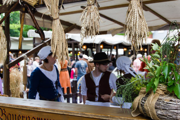 Obraz na płótnie Canvas Scene with wheat hanging from the top at a counter and blurry people dressed in medieval clothes behind. Selective focus