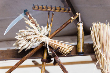 Miniature of scythe, flail, straw and rake to symbolize the ancient and traditional way of wheat harvest.