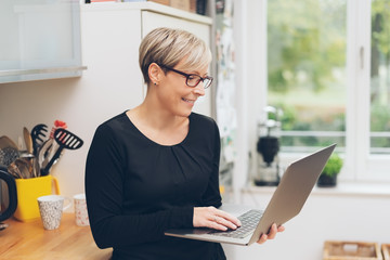 Smiling housewife using a handheld laptop