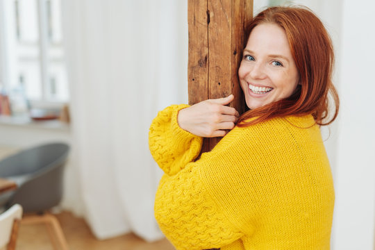 Young smiling woman hugging a wooden pole