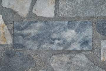 The floor surface is made of marble or granite tiles. In the center of a rectangular tile. Around the tiles of different shapes. Tiles have streaks of gray, beige color. Background, backdrop, texture.