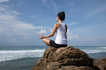 Fototapeta na wymiar Yoga woman clothing in white meditation at the seaside cliff edge