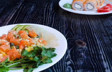 dish with rice and salmon sushi on a white plate on a dark background top side view poke